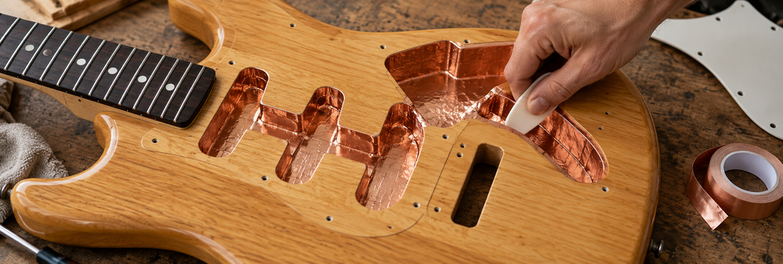 Illustrative scene of copper foil tape being burnished inside an electric guitar's pickup and control cavities