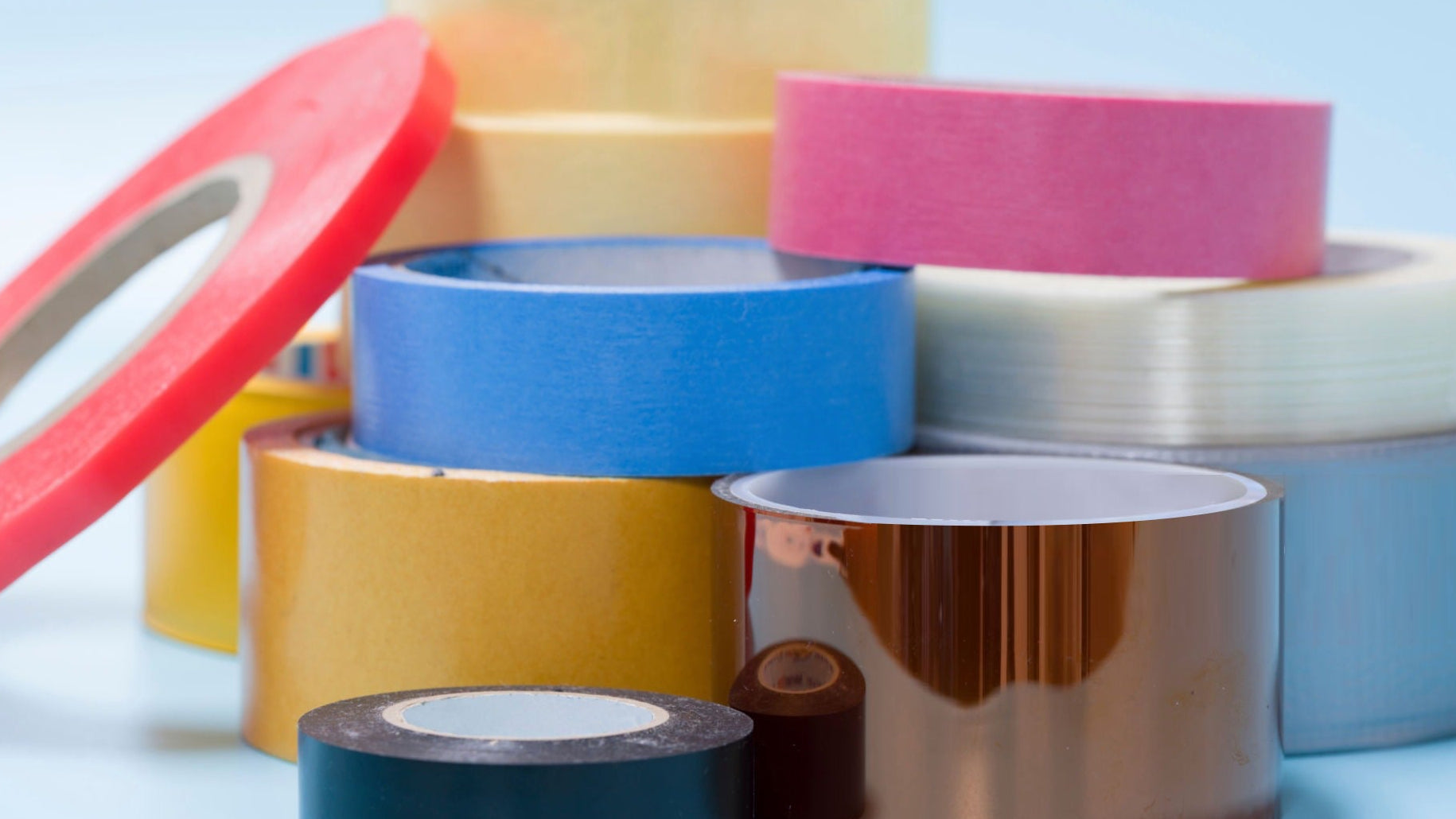 Assorted rolls of colorful tape on a light blue background
